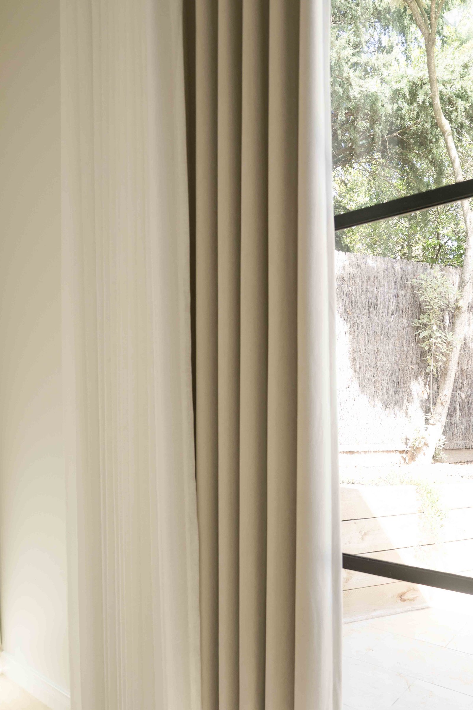 Light beige and sheer white curtains partially covering a window.