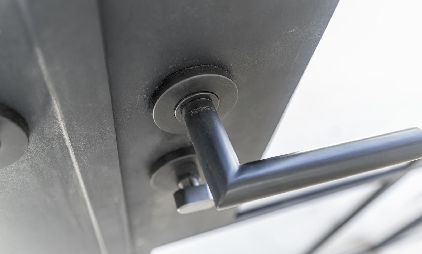 Close-up of a black modern door handle with the brand name Hafele engraved on it.